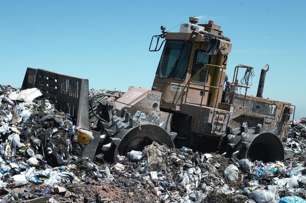 Trash compactor on landfill site