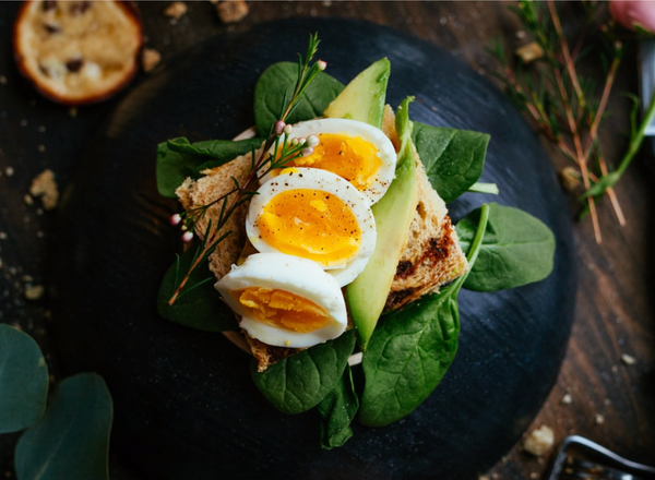 Boiled eggs and avocado toast on bed of spinach