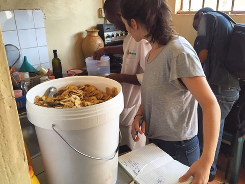 woman and bucket of plantain chips inside processing facility