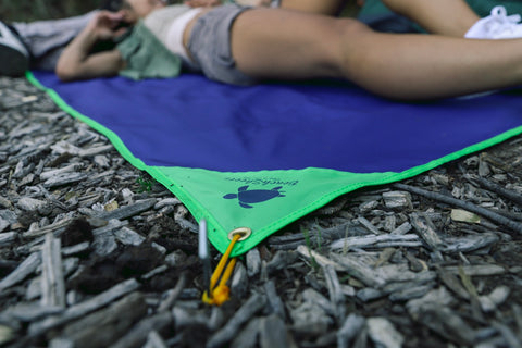 A couple using the ground stakes for their BeachSheetz Camp Blanket while camping