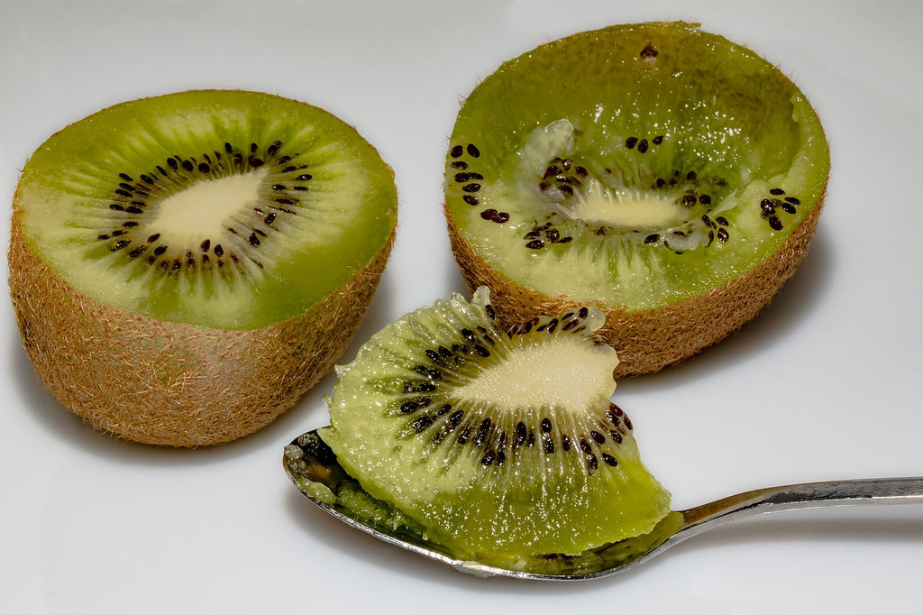 How to cut a kiwi: kiwi halves with the fruit scooped out on a spoon