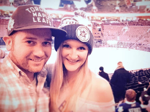 Andrew and Megan Kelly at a Toronto Maple Leafs game wearing Maple Leaf fan hats.