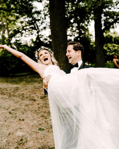 Andrew Kelly lifts up Megan Kelly on their wedding day. Megan's hand in the air, smile wide across her face.