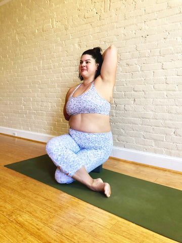 Woman does seated yoga pose up against a wall