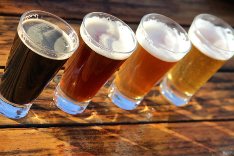 A flight of beers sits on a wooden table.