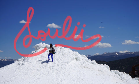 A picture of the owner on top of a snow covered mountain with the Loulii name written on top of  the picture