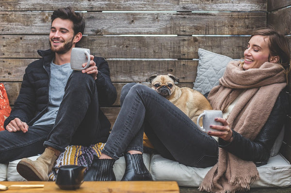 A man and woman drinking coffee with their dog