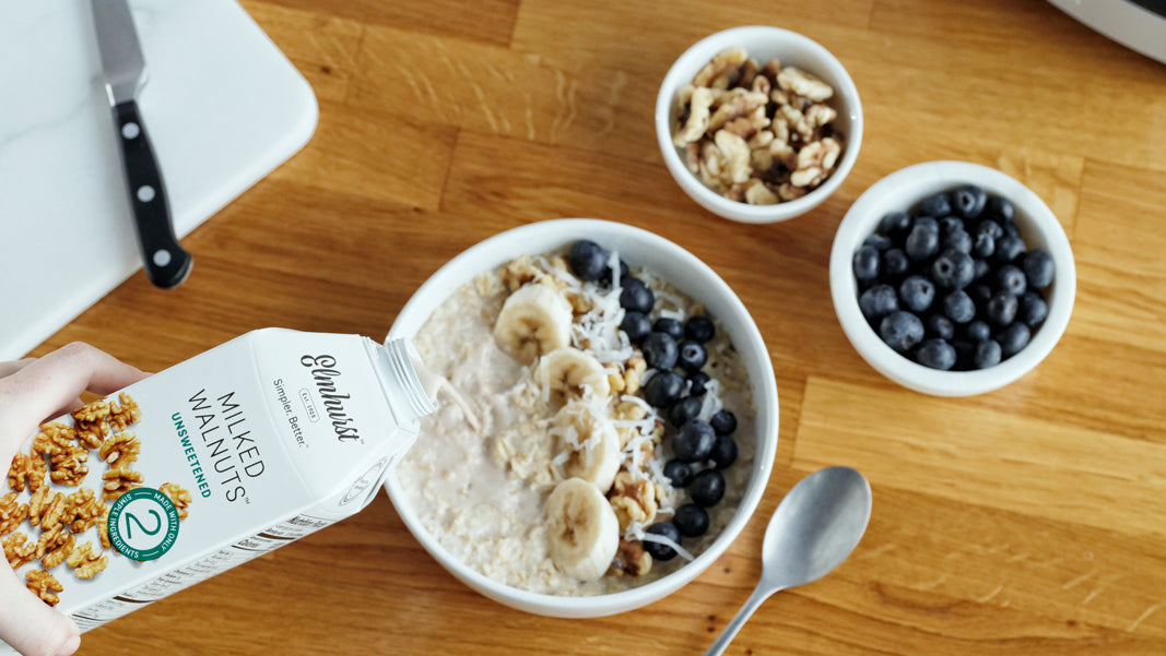 a bowl of oats, walnuts and blueberries with Elmhurst Walnut Milk