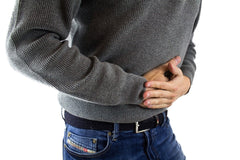 man holding his abdominal area - experiencing pain