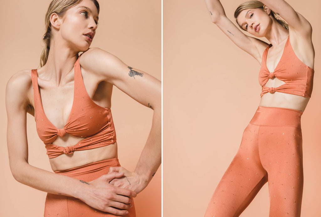 Model stretching in Twist sport bra top and active legging in color rust with rhinestones.