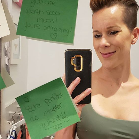 Kim taking a selfie in the mirror with positive notes all over the mirror