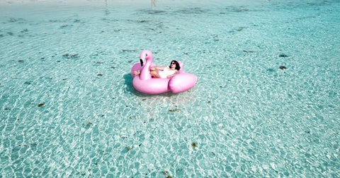 Femme allongée à la mer sur une bouée géante flamant rose de 190 cm