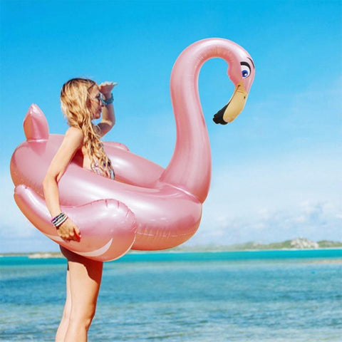 femme tient une bouée ronde flamant rose dorée sur la plage