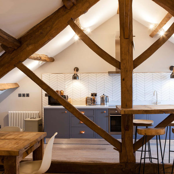 Industrial inspired kitchen interior with blue cabinets, exposed wooden beams and vintage lighting