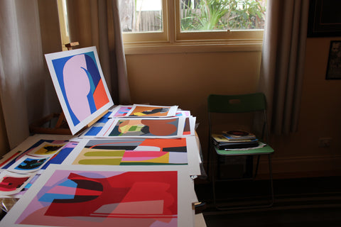 A table with multiple Philippa Riddiford Artworks laid out underneath a window in the sun 
