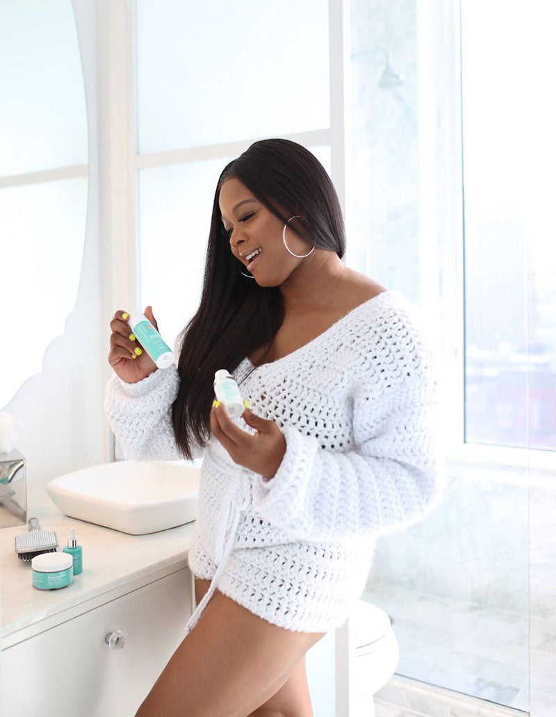 Young African American woman in bathroom admiring her collection of Urban Skin Rx® products
