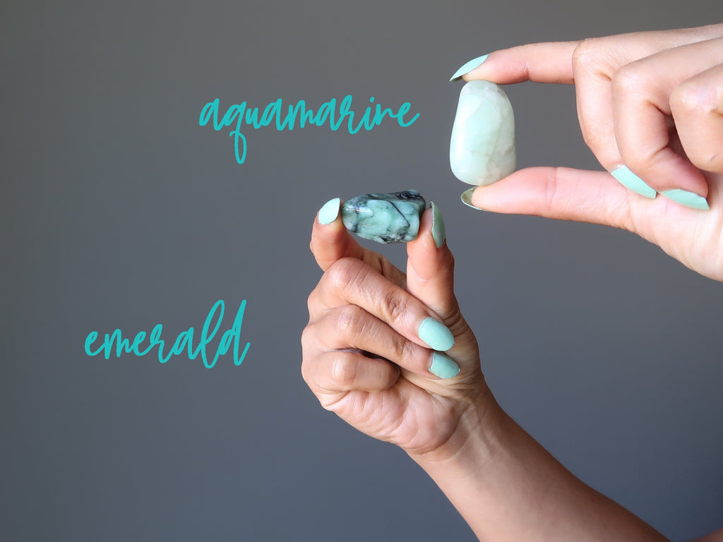 hands holding aquamarine and emerald tumbled stones