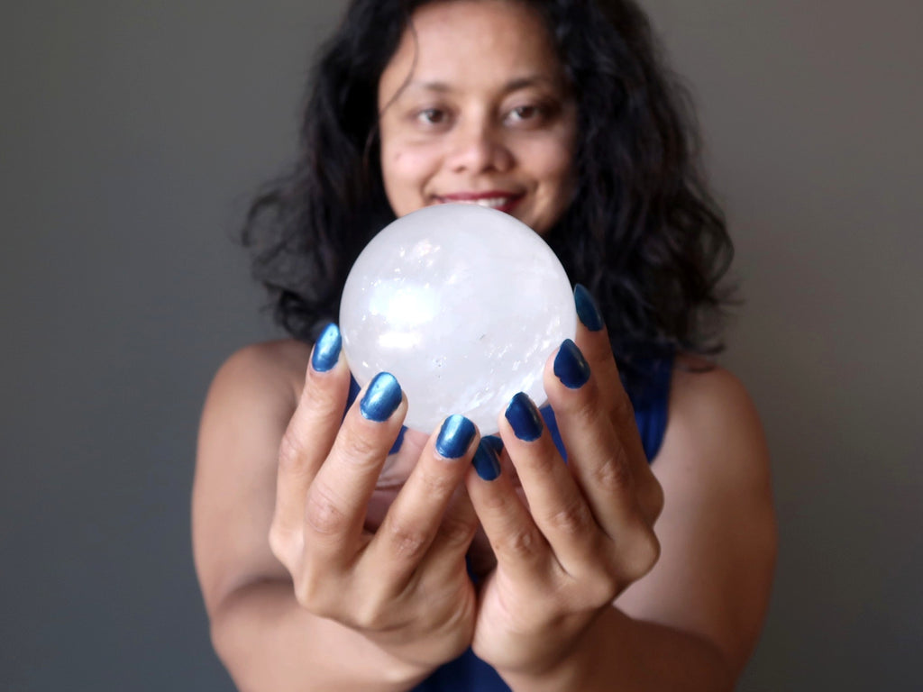 sheila of satin crystals ball gazing into a clear white calcite stone sphere