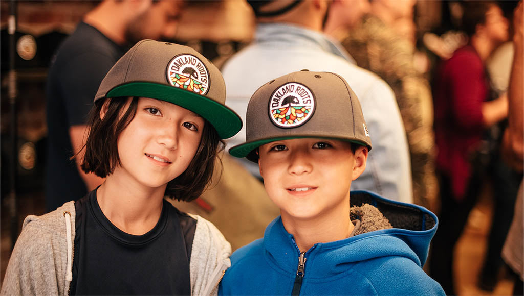 Two cute kids wearing Oakland Roots hats.